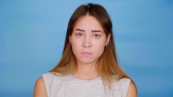 Tråkig kvinna i grå t-shirt nickar huvudet och säger ja på blå bakgrund — Stockvideo
