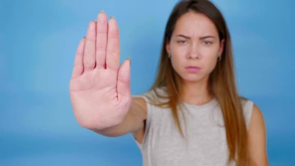 Serious angry woman in gray T-shirt holds out palm to the camera, says stop — Stock Video