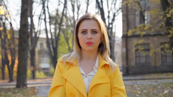 Woman in cloak, blouse stands, looks camera in the park, camera moves girl — Stock Video