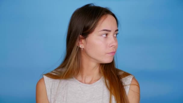 Frau schaut sich um hebt Hände weiß nicht, was sie auf blauem Hintergrund wählen soll — Stockvideo