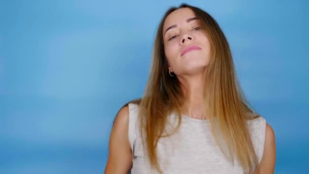 Hermosa mujer con el pelo largo en camiseta gris está bailando sobre fondo azul — Vídeos de Stock