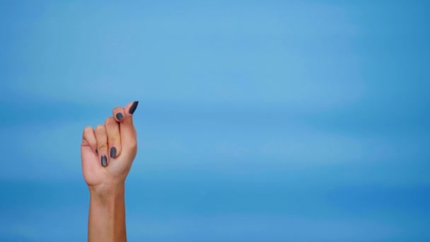 Kvinnelig hånd knipser med fingrene på blå bakgrunn med kopiplass for tekstplassering – stockvideo