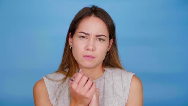 Mujer asustada en camiseta gris miedo, cubre la cara con las palmas sobre fondo azul — Vídeos de Stock