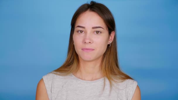 Confident woman in gray t-shirt nods head and says yes on blue background — Stock Video