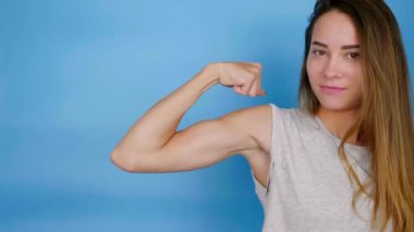 Güçlü güçlü bir kadın kaslarını gösteriyor, başparmağını kaldırıyor, öpüşüyor gibi.
