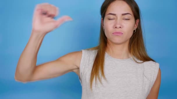 Mooie grappige vrouw in grijs T-shirt heft hand en toont duim naar beneden, afkeer — Stockvideo