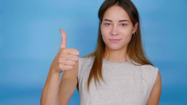 Positiv kvinna i grå t-shirt höjer handen, visar tummen upp, liksom och ler — Stockvideo