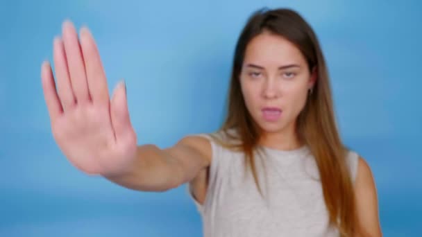 Beautiful serious woman in gray T-shirt holds out palm to the camera, says stop — Stock Video