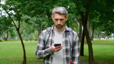 Gezgin blogcu akıllı telefondaki GPS haritalarını kullanarak parkı gezer.