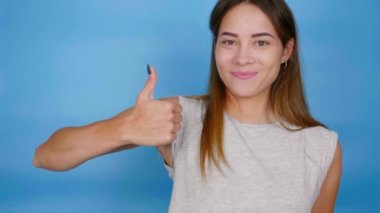 Gri tişörtlü olumlu kadın elini kaldırdı, başparmağını kaldırdı ve gülümsedi.