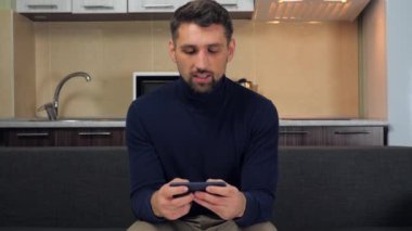 Adam duygusal olarak akıllı telefondan oyun oynar, kazanır, zaferle sevinir, gülümser.