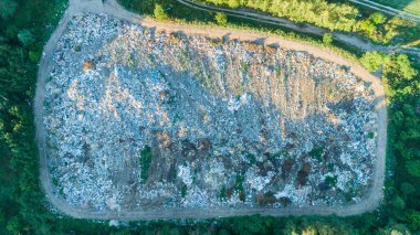 Yaz günbatımında yeşil ormanın yakınındaki hava manzaralı çöplüğü kapatın.