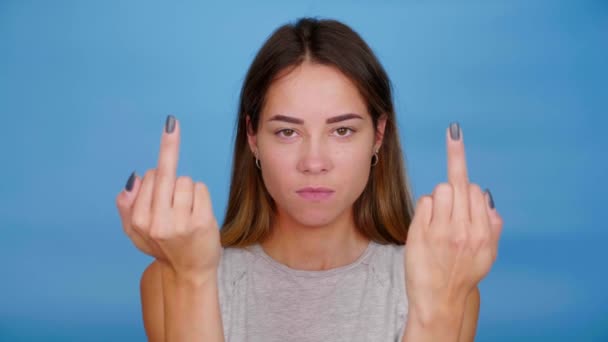 Serieuze vrouw in grijs t-shirt toont middelvinger op blauwe achtergrond — Stockvideo