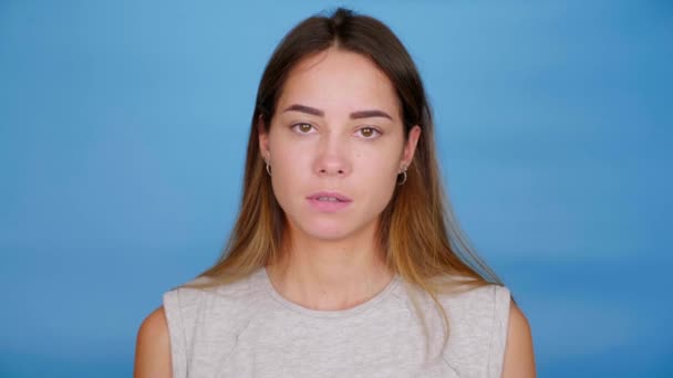 Känslomässig allvarlig kvinna i grå t-shirt visar långfingret på blå bakgrund — Stockvideo