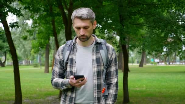 Человек путешествия блоггер прогулки парк глядя достопримечательности с помощью GPS карты в смартфоне — стоковое видео