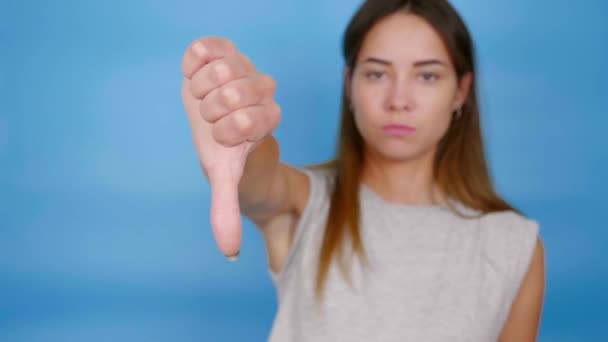Vacker seriös kvinna i grå T-shirt höjer handen, visar tummen ner, ogillar — Stockvideo