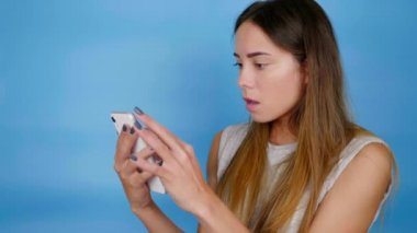 Gri tişörtlü kadın akıllı telefon kullanıyor, online mağazada fiyatlara şaşırıyor.