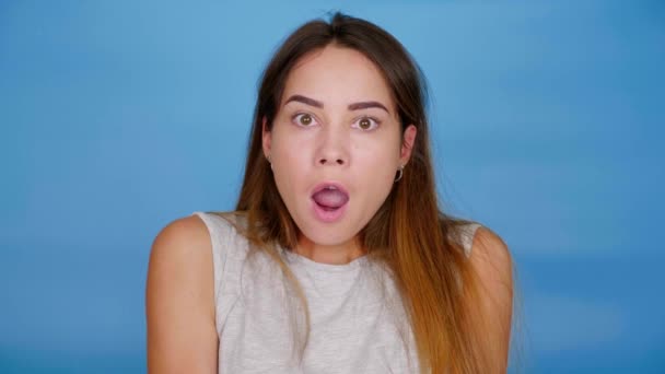 Geschockte Frau wendet sich an Kamera auf blauem Hintergrund mit Kopierraum — Stockvideo
