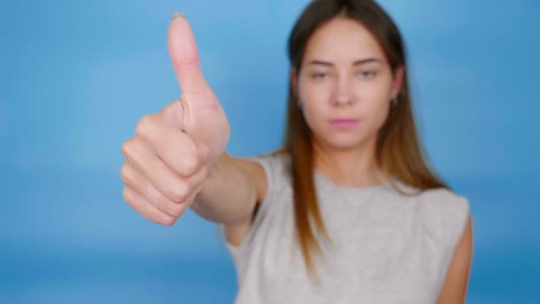 Beautiful Woman Gray Shirt Raises Hand Shows Thumb Blue Background — Stock Video