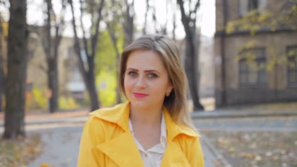 Ευτυχισμένη Γυναίκα Κίτρινο Μανδύα Λευκά Χαμόγελα Μπλούζα Στέκεται Φθινόπωρο Πάρκο — Αρχείο Βίντεο