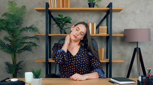 Tired woman in home office massages neck pain after long hard work at laptop