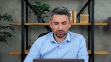 Gülümseyen erkek öğretmen internet üzerinden kablosuz kulaklıkla öğrencilerle iletişim kuruyor görüntülü sohbet konferansı web kamerası dizüstü bilgisayarı. İçişleri Bakanlığı 'ndaki işadamı çalışanları konuşuyor