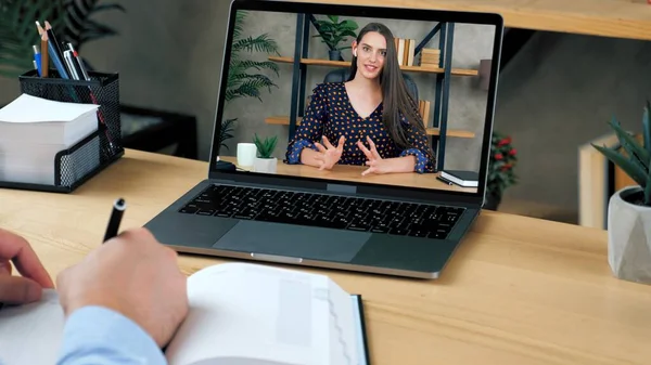Konferans videosuyla çalışan erkek öğrenci bilgisayarına not defteri yazmış.