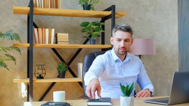 Merkez ofisteki masada oturan adam kablosuz kulaklık takıyor.