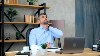 Yorgun adam dizüstü bilgisayar kullandıktan sonra boyun masajı yapıyor, kötü duruş