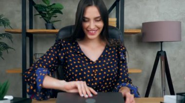 Güzel, gülümseyen esmer kadın öğretmen ofis odasının masasında oturuyor ve dizüstü bilgisayar kullanmaya başlıyor. Kadın klavye üzerindeki bilgisayar türleri üzerinde çalışır imleç dokunaçlarını kontrol eder. Kamera yakınlaştır