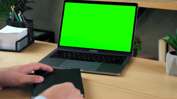 緑の画面のラップトップコンピュータの概念 ウェブカメラのビデオ通話会議によるオンライン遠隔学習教育 自宅のオフィスで男の学生は テーブルの勉強はノートブックにペンで情報を書きます — ストック動画