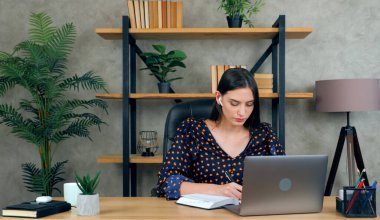 Kadın not defteri çalışmasında öğretmeniyle online video konferans görüşmesi yapıyor.