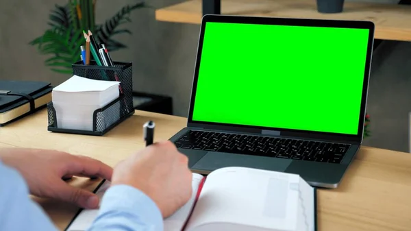 남자 학생 연구는 수첩에 정보를 쓰죠. 녹색 화면 노트북 컴퓨터 — 스톡 사진