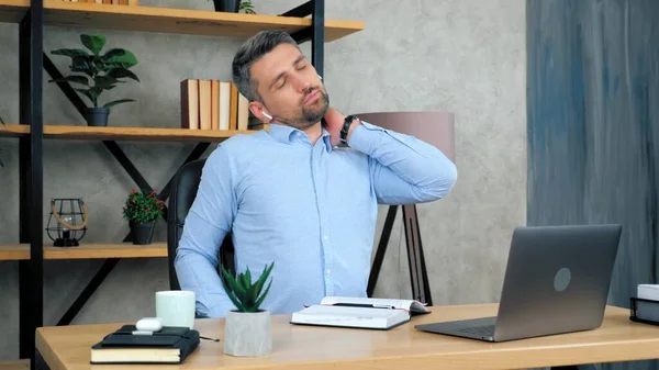 Tired man massages neck after using laptop computer long time, poor posture