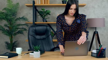 Ofiste masa başında çalışan iş kadını dizüstü bilgisayar kullanıyor.