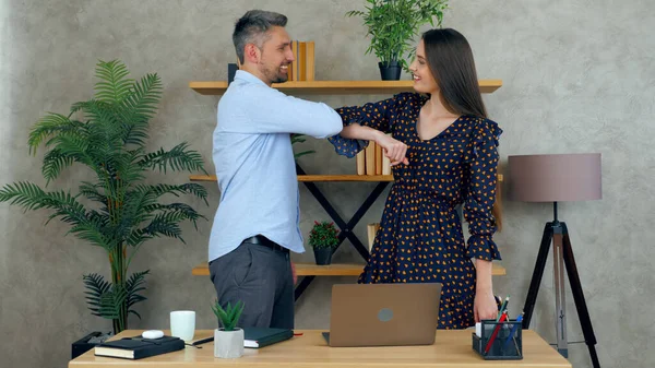 Lachende vrouw en man begroeten ellebogen medewerkers werken samen met laptop in kantoor — Stockfoto