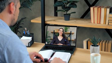 Yurt içi ofisindeki erkek öğrenci konferans görüntülü arama bilgisayarıyla çalışıyor.