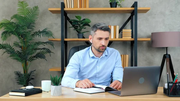 Бизнесмен слушает онлайн видео конференцию для сотрудников — стоковое фото