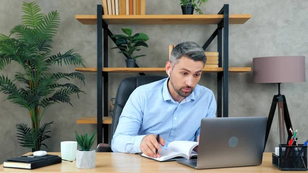 Человек в домашнем офисе использует ноутбук, поиск информации в ноутбуке — стоковое фото