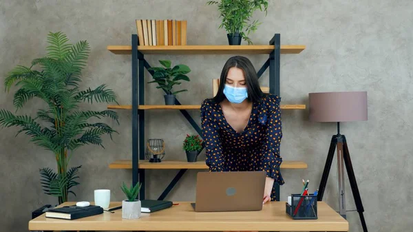 Businesswoman wear protective medical mask on face work in office using laptop