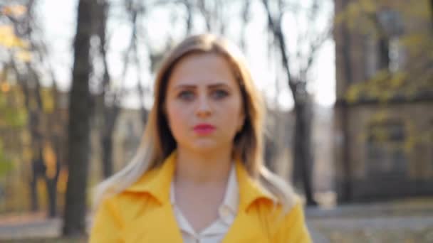 Κοντινό πλάνο γυναίκα σε μανδύα περίπτερα μπλούζα φαίνεται κάμερα στο πάρκο, κάμερα κινείται κορίτσι — Αρχείο Βίντεο