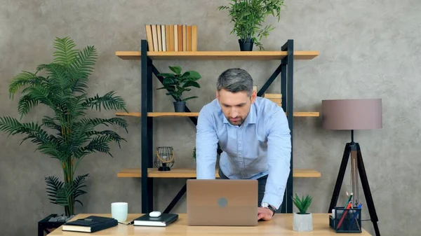 Affärsman chef SEO arbetar på hemmakontoret stående vid bordet med bärbar dator — Stockfoto