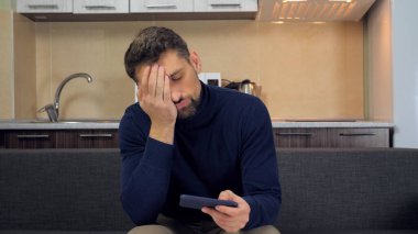 Üzgün adam oyuncu akıllı telefondan oyun oynar sonuç facepalm ile tatminsiz kaybeder