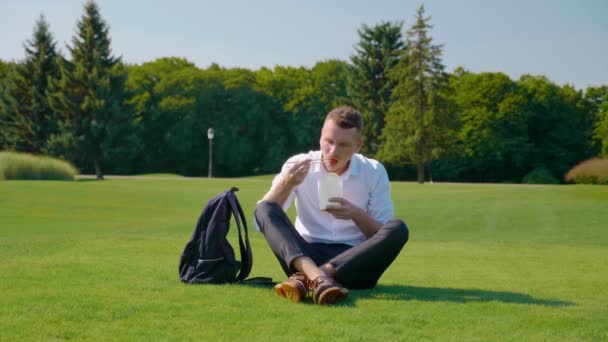 De mens eet vegetarische lunch met een ecologisch pakket, fronst en toont afkeer — Stockvideo