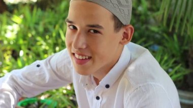 Kameraya bakarak mutlu Arap Müslüman Genç adam. Genç Müslüman çocuk bir medrese Islam hakkında bilgi edinin. Bir medrese İslam dini okuludur. Öğrenci kuran muhammed öğretilerini çalışma ve duaları ezberden