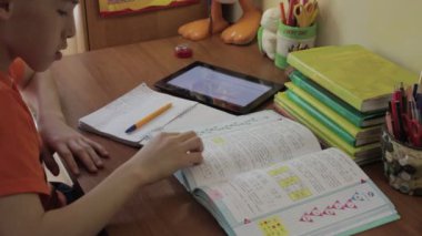 Tablet yazılı olarak defter ile tablo okuyan oturan öğrenci