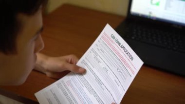 Genç bir adam için bir araç kredisi uyguluyor. Kredi başvuru formu bir kağıt sayfası