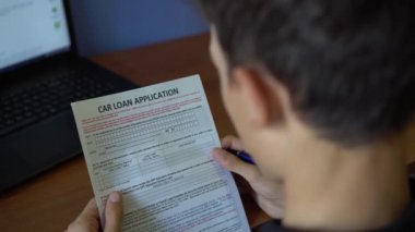 Genç bir adam için bir araç kredisi uyguluyor. Kredi başvuru formu bir kağıt sayfası