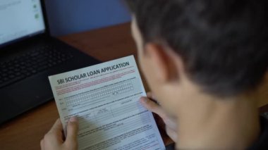 Genç bir adam Sbi bilgin kredi ayırıyor. Kredi başvuru formu bir kağıt sayfası