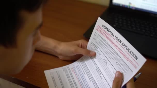 一个年轻人申请个人贷款 在纸页上的信用申请表 — 图库视频影像
